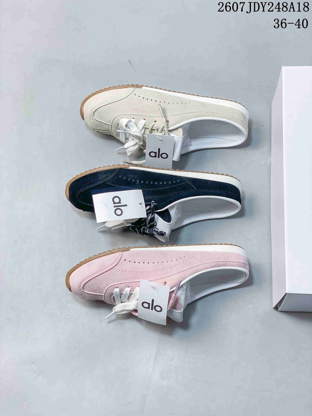 Pink, navy and cream alo mule sneakers arranged side by side, showing their open-heel profiles and gum-colored outsoles.
