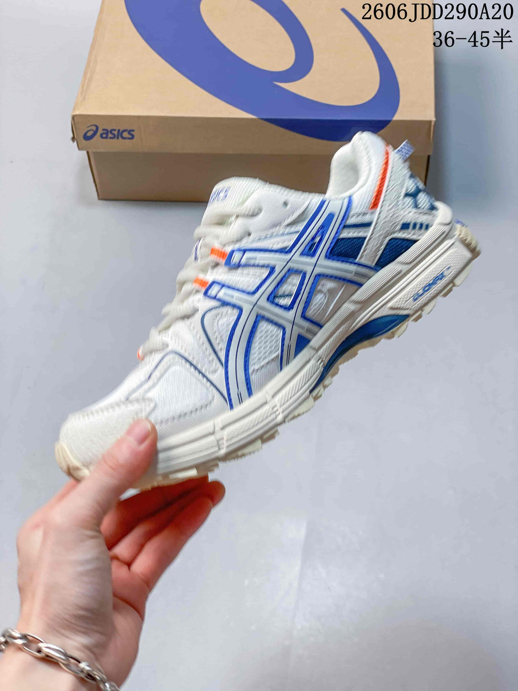 Side profile of the white sneaker showing blue structural detailing, orange accents, and the textured outsole.