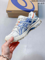 Side profile of the white sneaker showing blue structural detailing, orange accents, and the textured outsole.