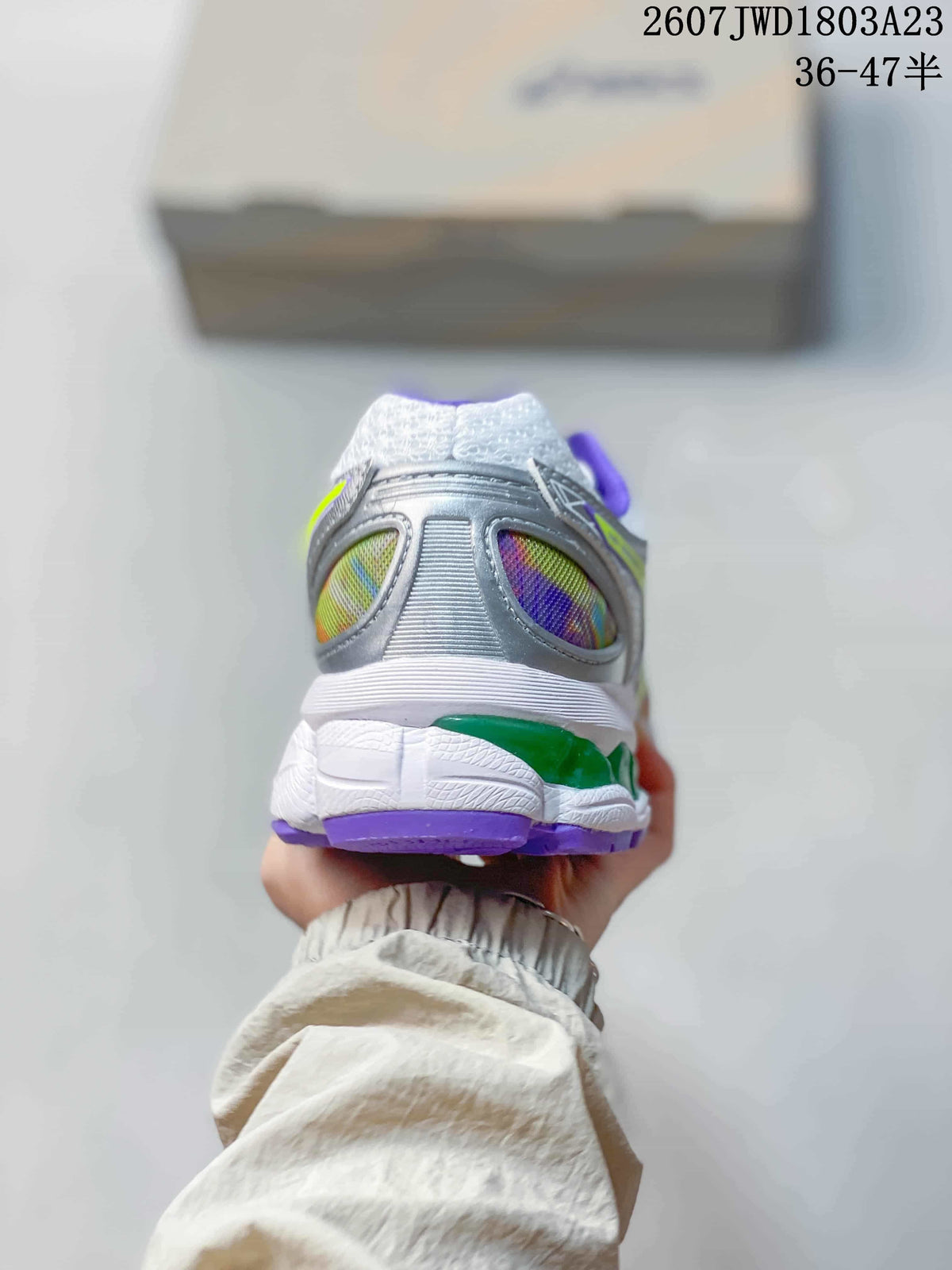 Rear view of an ASICS sneaker showing the padded heel, silver panels, multicolor inserts, and purple outsole edge.