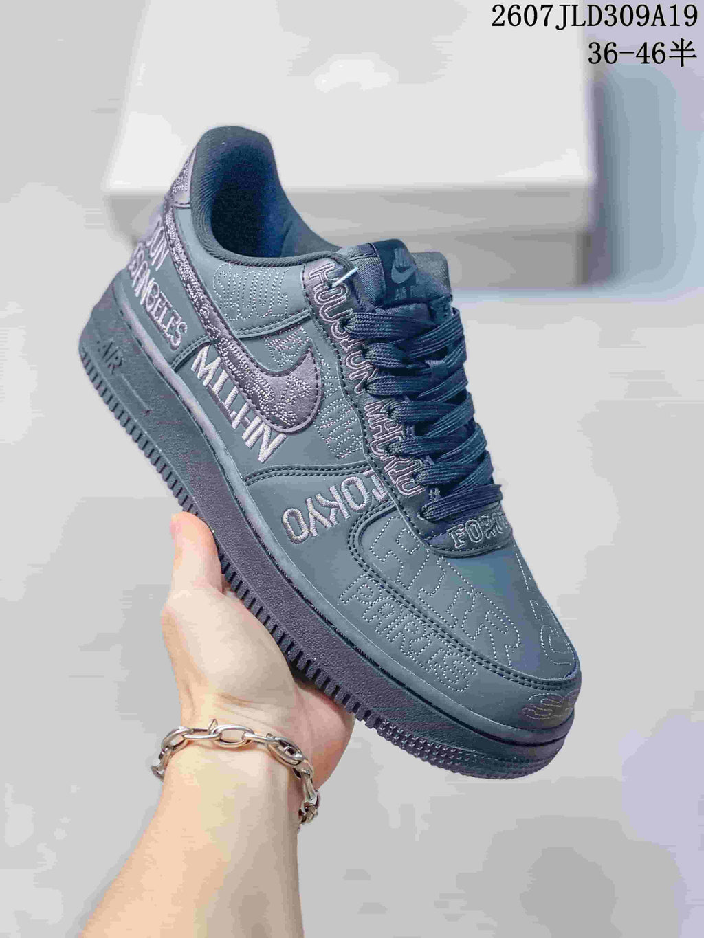 Three-quarter side view of the dark gray Nike Air Force 1 sneaker showing the Swoosh, low-top shape and graphic lettering.