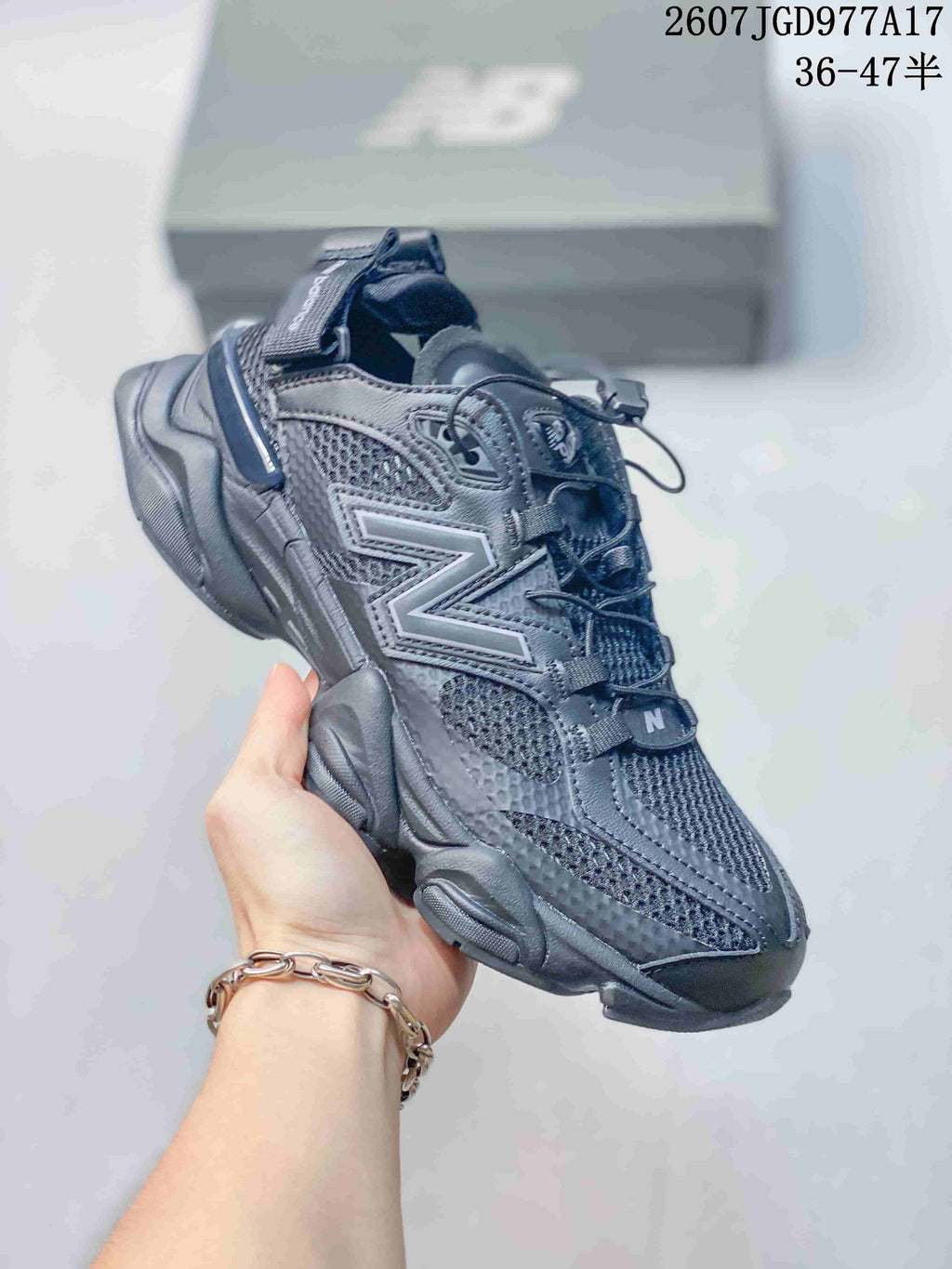 Three-quarter side view of the dark New Balance 9060 mule sneaker showing the mesh upper, pull tabs, open heel, and chunky outsole.