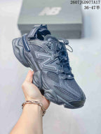 Three-quarter side view of the dark New Balance 9060 mule sneaker showing the mesh upper, pull tabs, open heel, and chunky outsole.