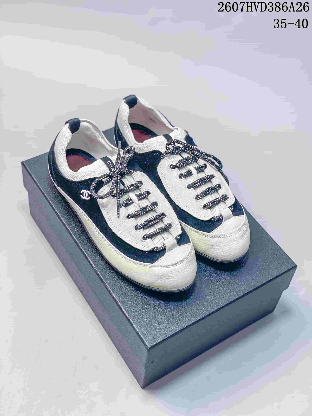 Front three-quarter view of black and white low-top sneakers with rounded toes and decorative laces.