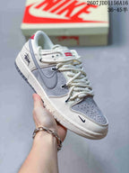 Close side view of an off-white and grey sneaker showing the Swoosh, red tongue label, perforated toe box and graphic heel detail.
