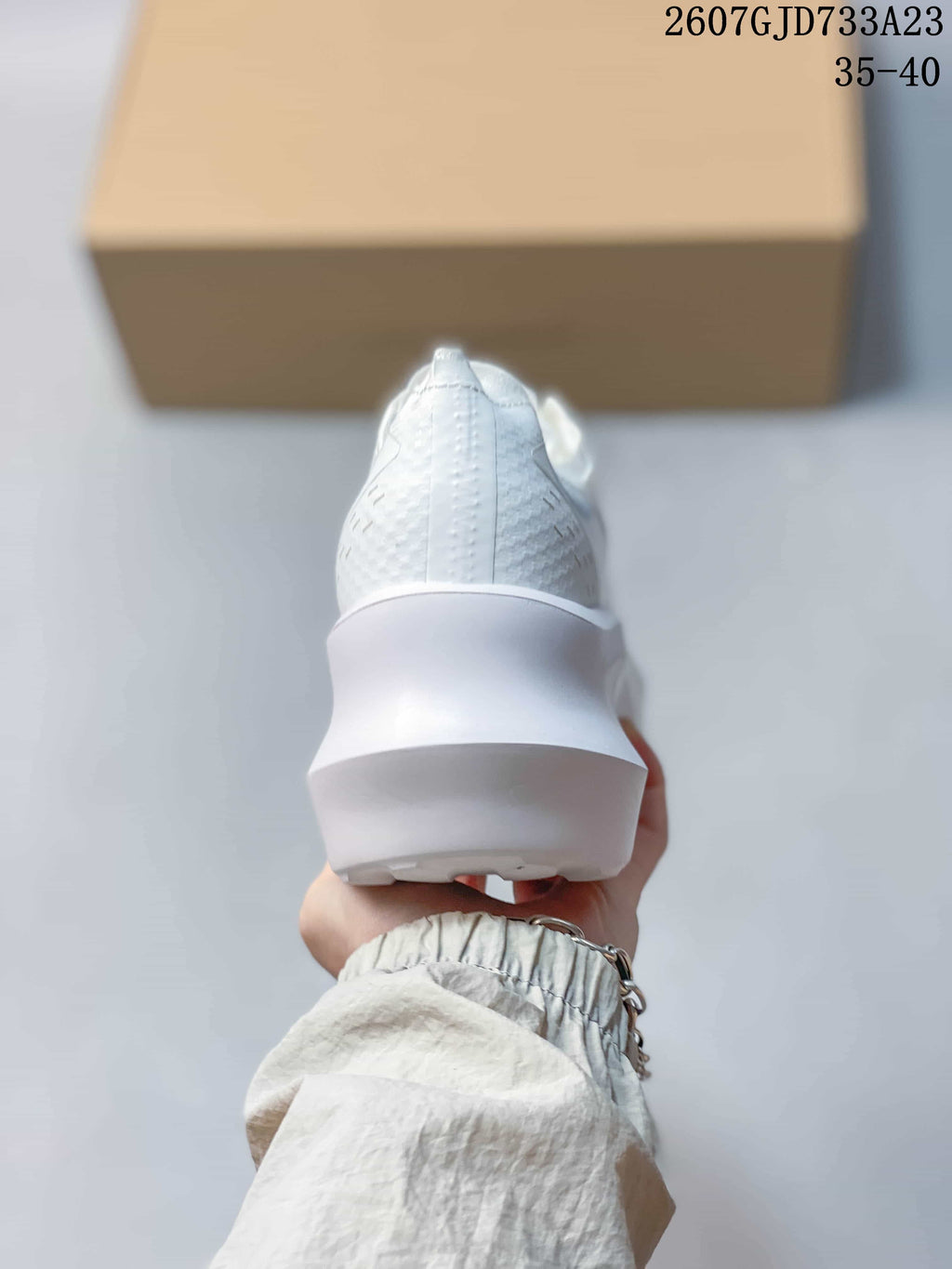 Rear view of the white sneaker showing the textured heel upper and thick sculpted sole.