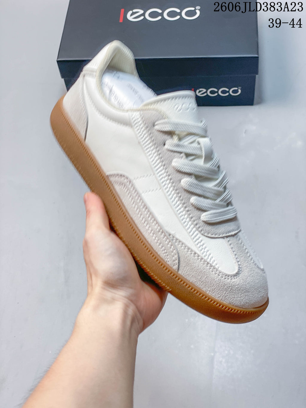 Angled view of the off-white sneaker showing the side panels, textured toe overlay, and gum-colored sole; image overlay shows sizes 39–44 and code 2606 JLD383A23.