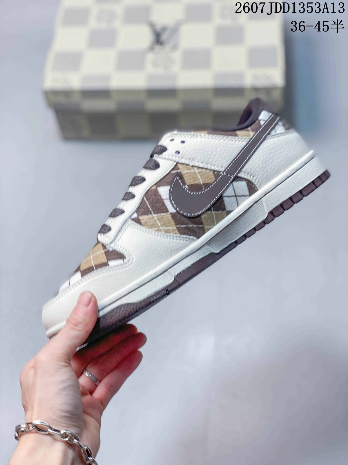 Side profile showing the white upper, brown plaid panels, dark swoosh, and layered sole.