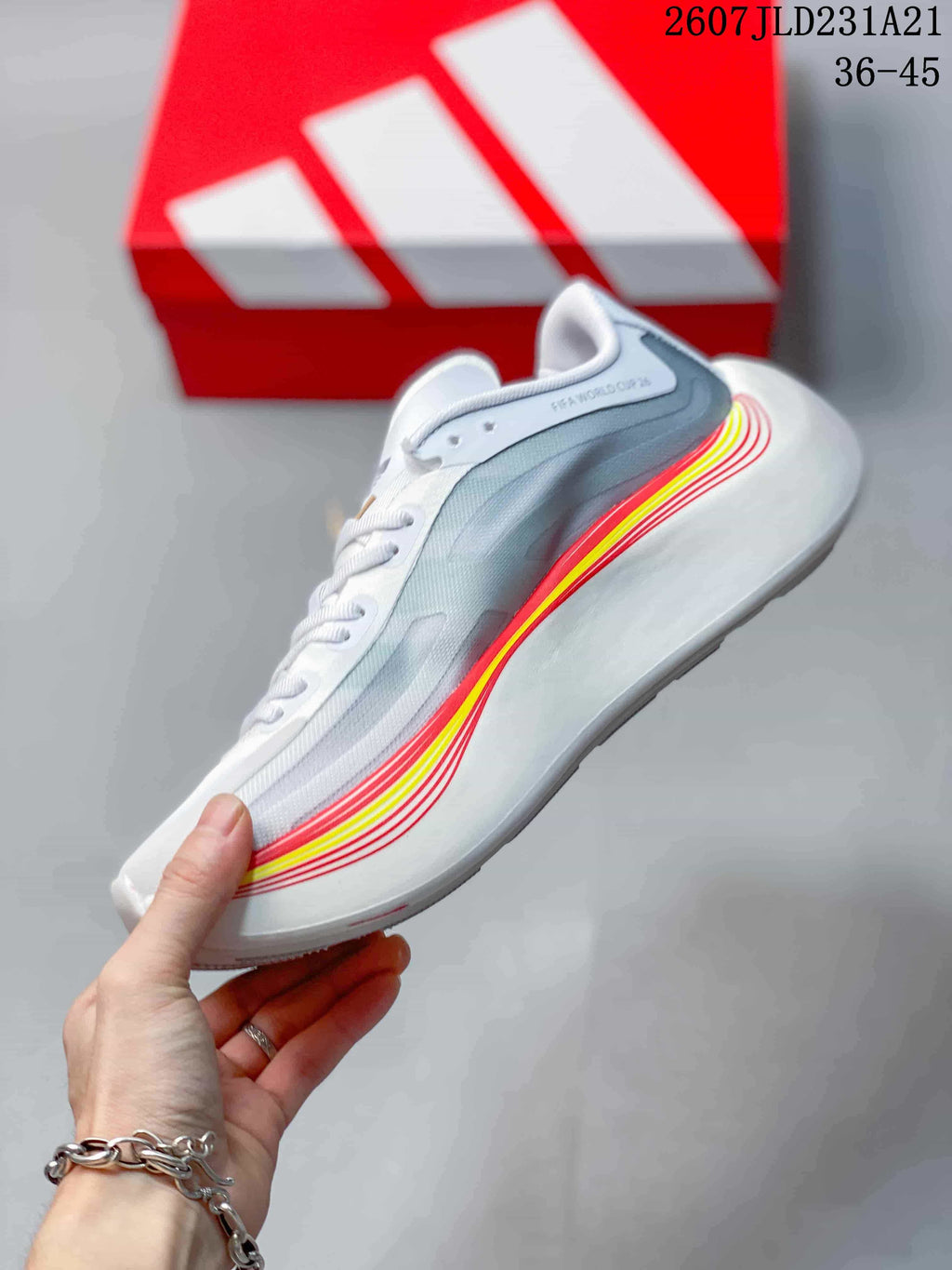 Side profile showing the grey upper, white midsole, and red and yellow layered accent stripes.