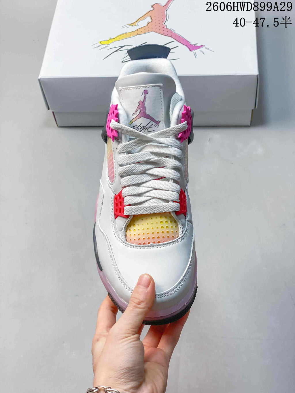 Front view of the sneaker showing white laces, pink supports, and a multicolor gradient panel.