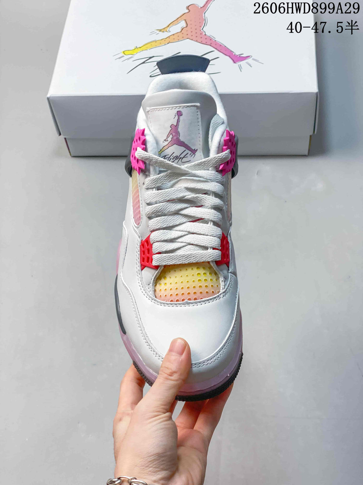 Front view of the sneaker showing white laces, pink supports, and a multicolor gradient panel.