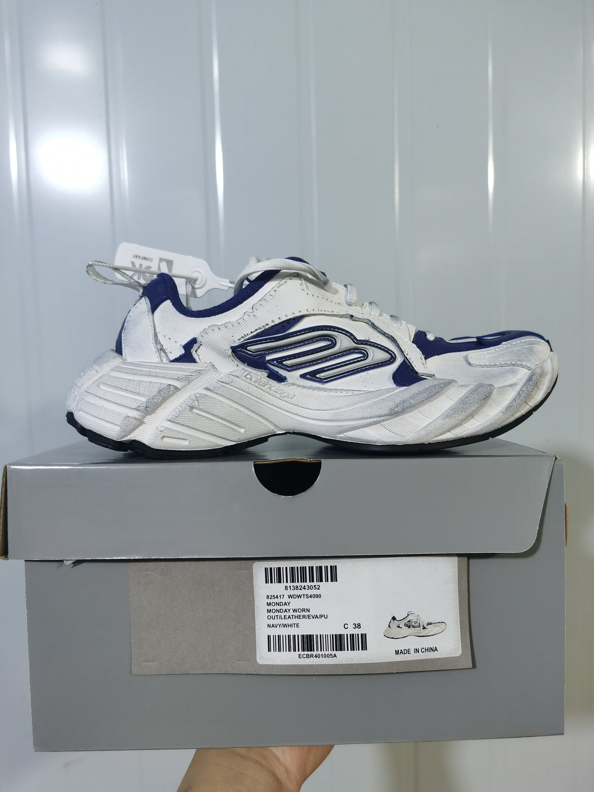 Side view of the navy and white sneaker resting on its box; the box label shows style code WDWTS4090, color NAVY/WHITE, and size C 38.
