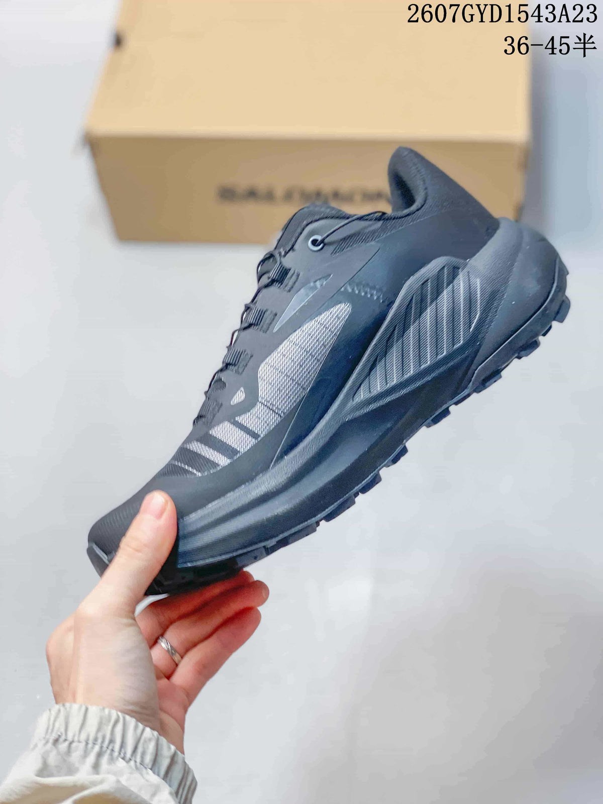 Side profile of a dark gray and black Salomon Genesis trail running shoe showing layered upper panels, mesh sections, midsole, and outsole lugs.