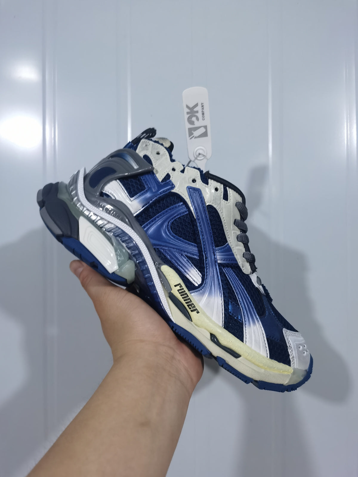 Close angled view of the Balenciaga Runner sneaker showing the navy and beige upper, contrast overlays and textured sole.