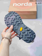 Close-up of the hiking shoe's lugged outsole, with Norda packaging in the background.