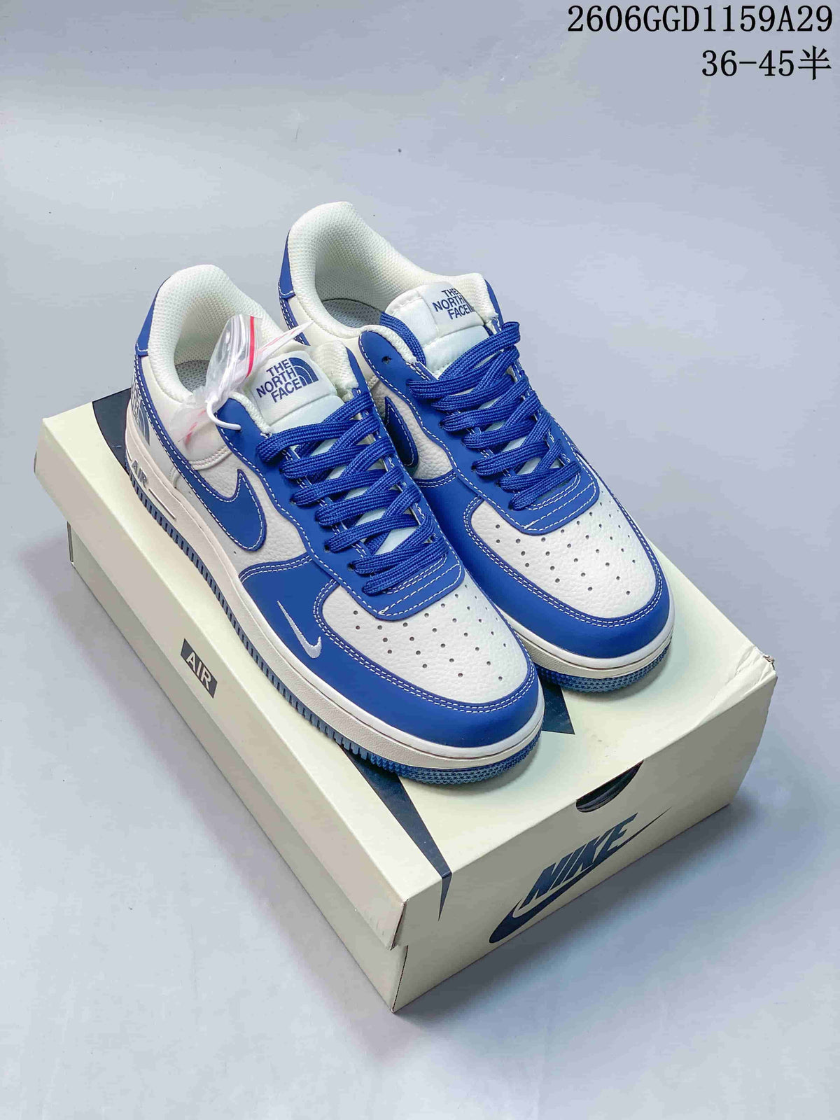 Pair of white and blue low-top sneakers with The North Face branding on the tongues, displayed on a shoe box.