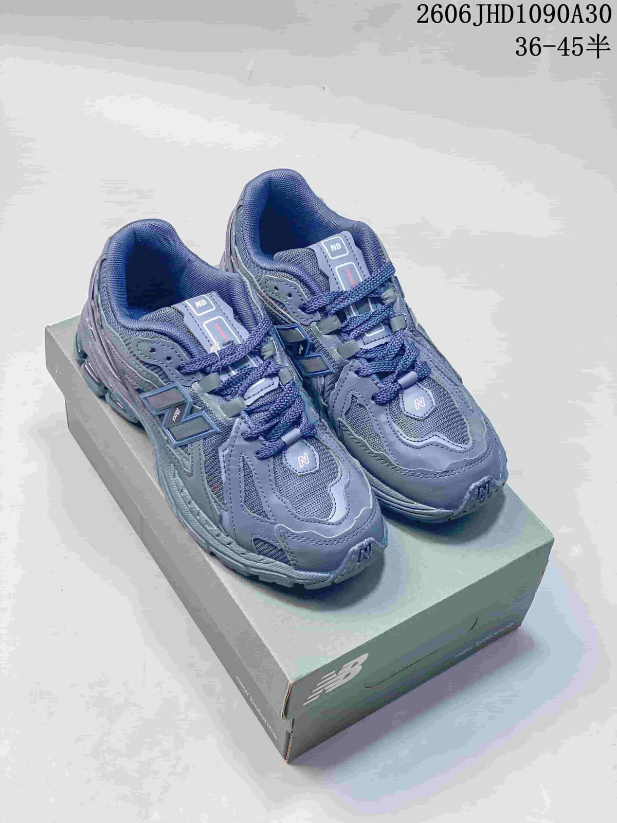 Pair of blue-gray New Balance M1906RA sneakers shown from above on a shoebox.