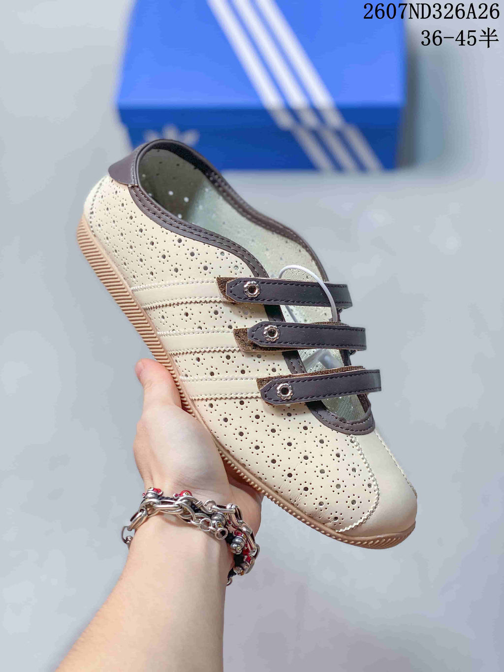 Angled side view highlighting the perforated cream upper, brown trim and three strap closures.