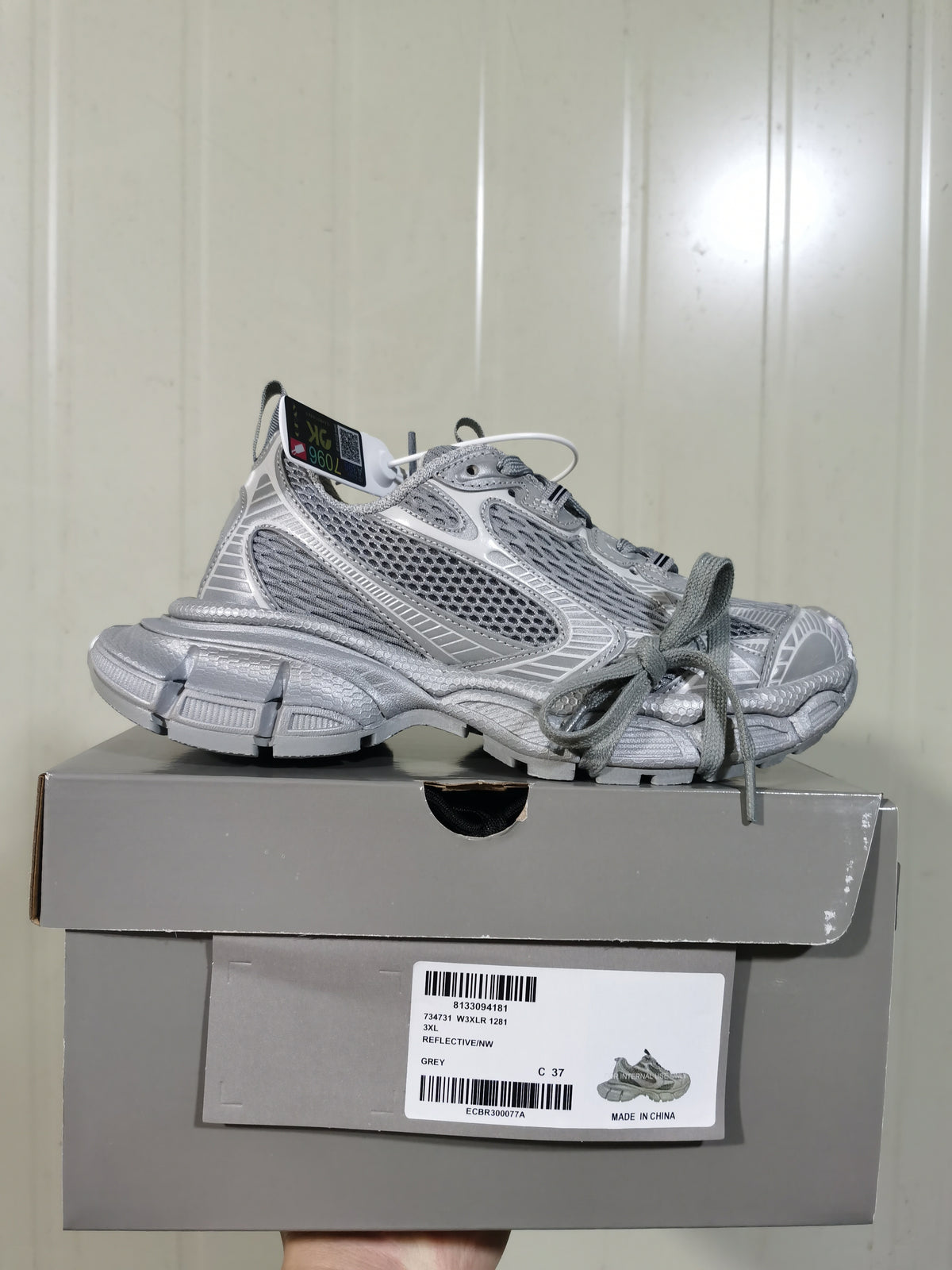 Side view of the grey sneaker resting on its box; the visible label includes style reference 1281, grey color and sample size C 37.