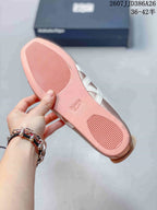 Underside of a pink shoe showing the flat outsole and textured tread zones, with the shoe box in the background.