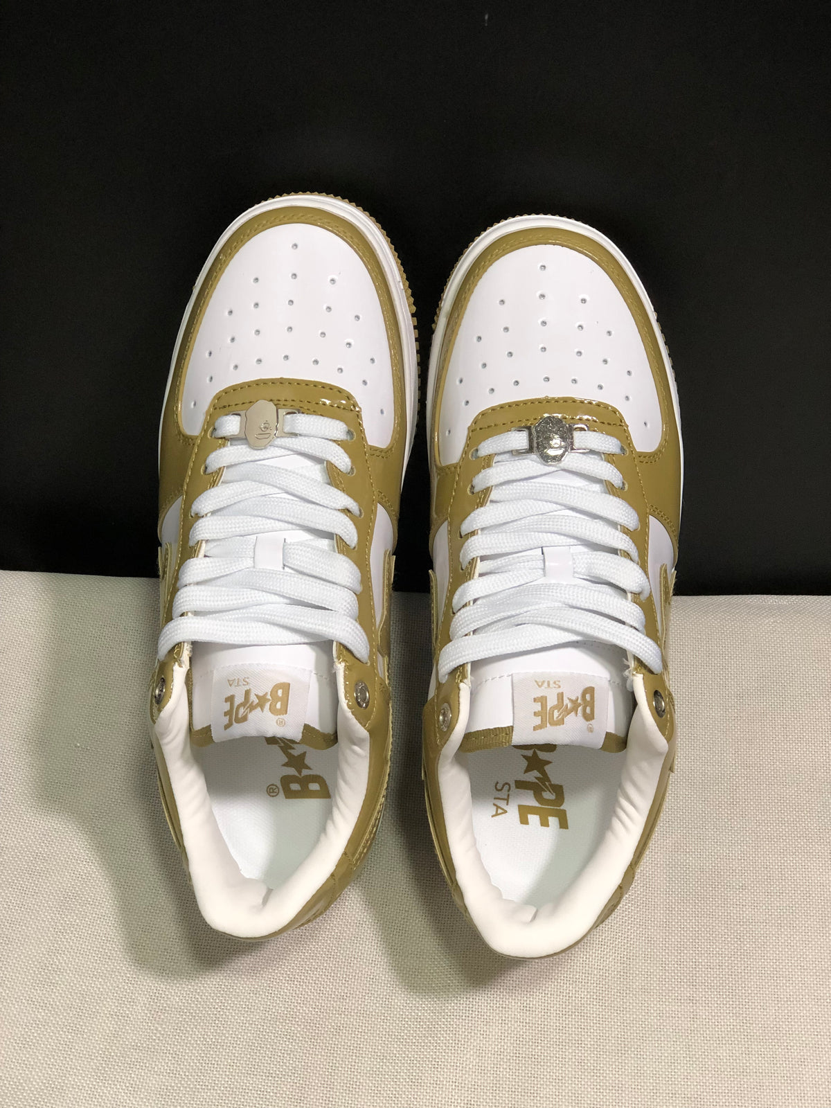 Top-down view showing white perforated toe panels, white laces, olive overlays, and tongue branding.