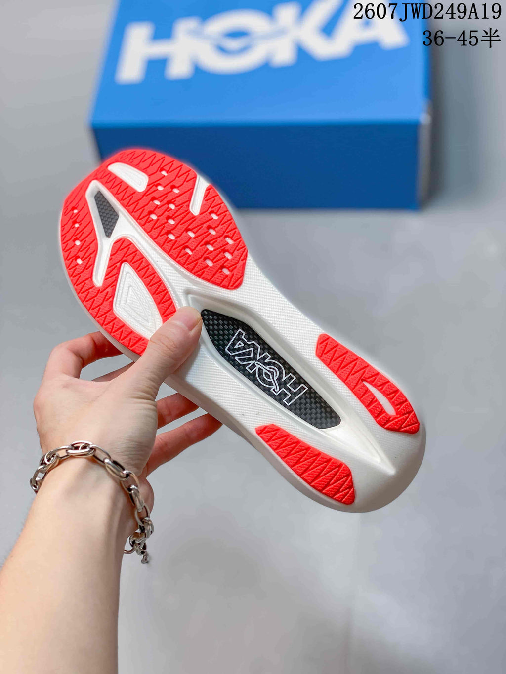 Close-up of the white outsole with red traction sections and a visible Hoka insert detail.