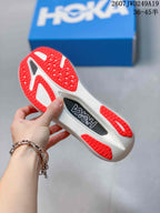 Close-up of the white outsole with red traction sections and a visible Hoka insert detail.
