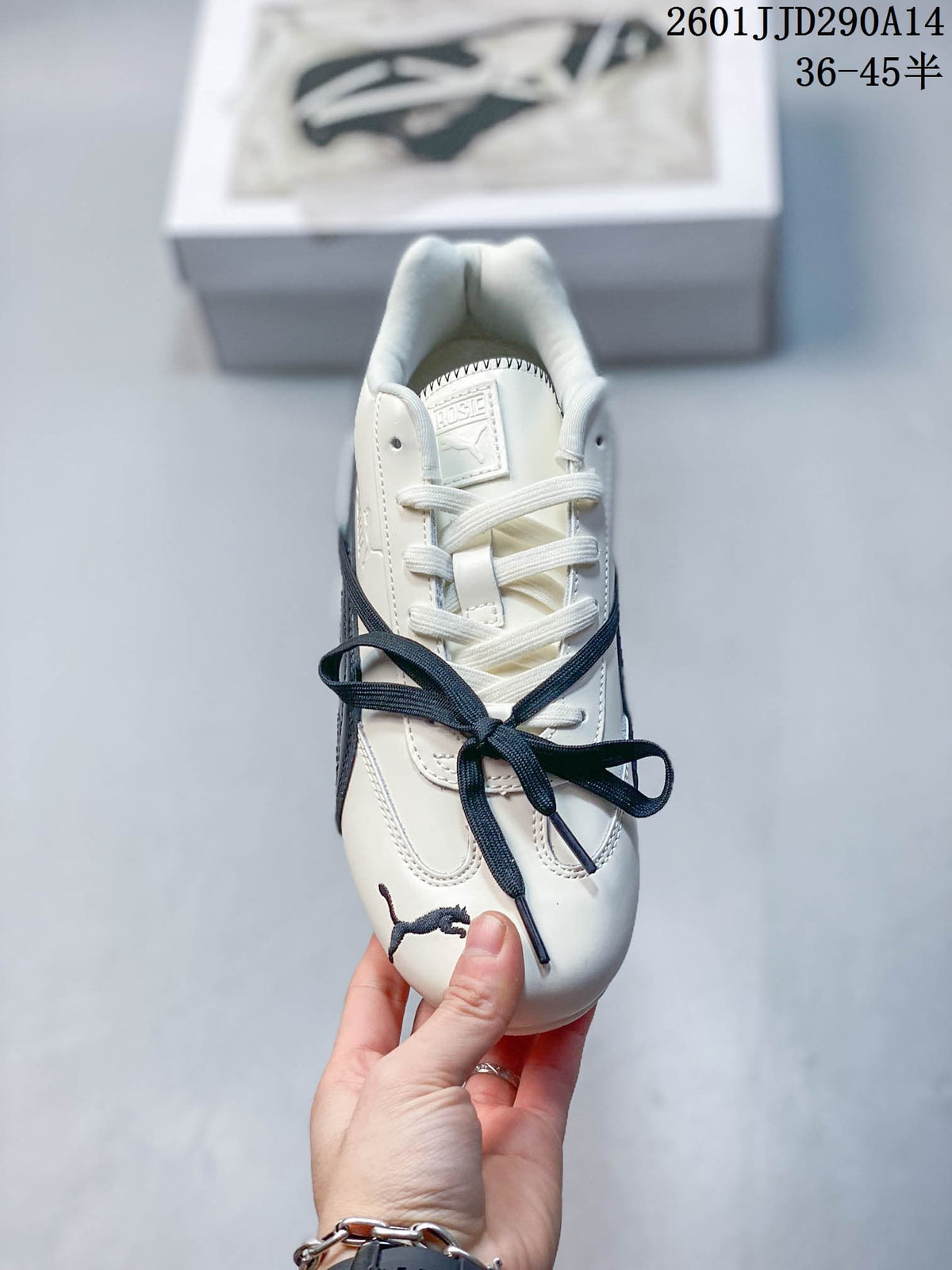 Top view of an off-white PUMA sneaker with white laces, navy lace detail, padded collar, and tongue branding.