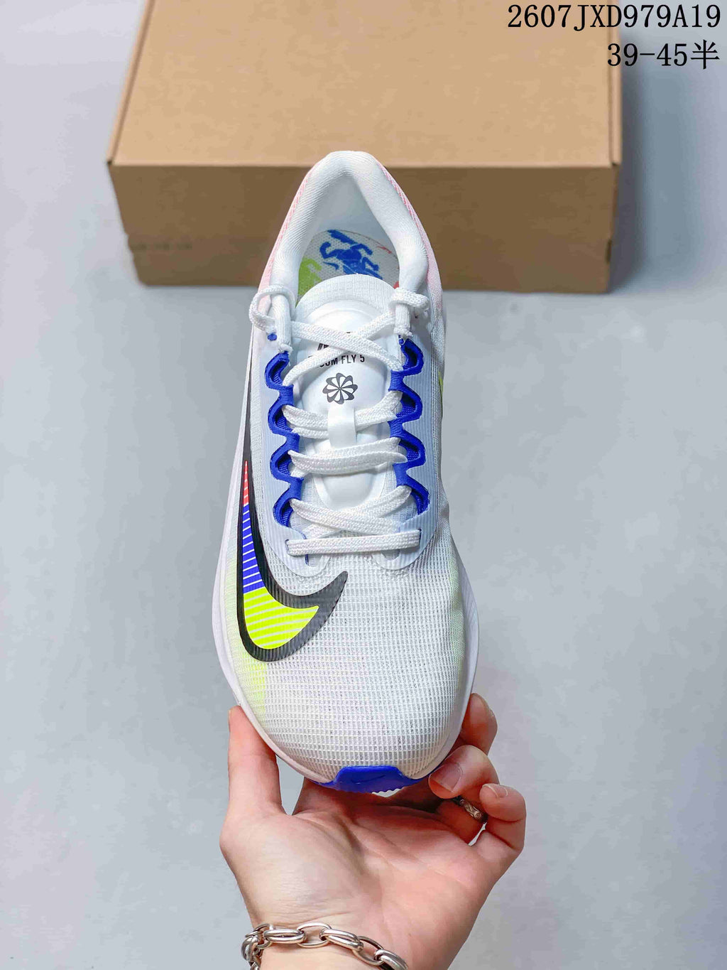 Top view of a white Nike running shoe with blue lace loops, white laces and a multicolor Swoosh.
