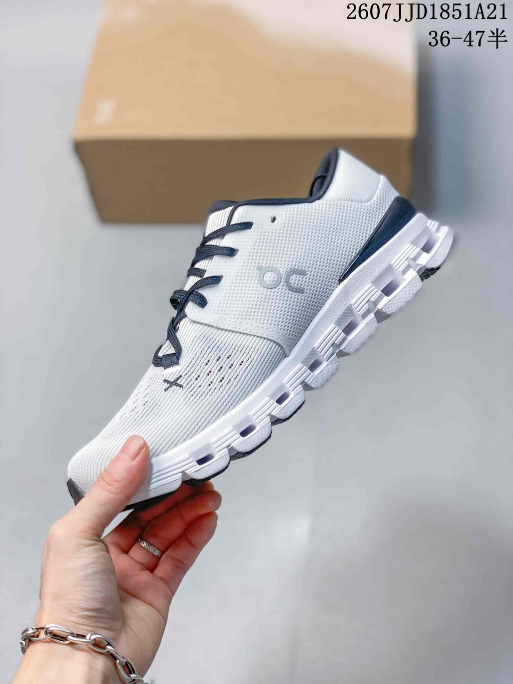Side profile of the white low-top sneaker showing the knit-style upper, On side branding, laces, and segmented sole.