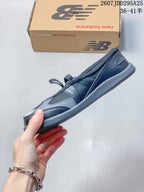 Side profile showing the low-profile silhouette, layered black and gray upper, strap, laces, and slim gray outsole.