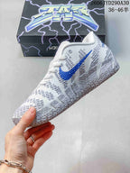 Side view of the white and gray shoe with a blue Swoosh and textured overlays.