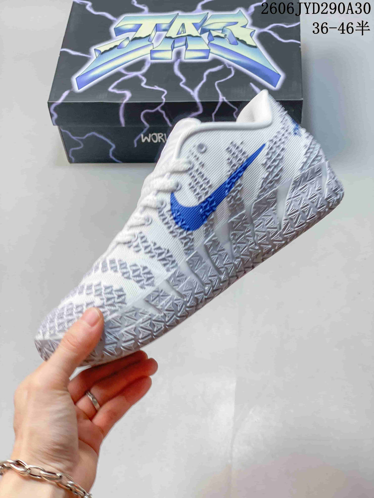 Side view of the white and gray shoe with a blue Swoosh and textured overlays.