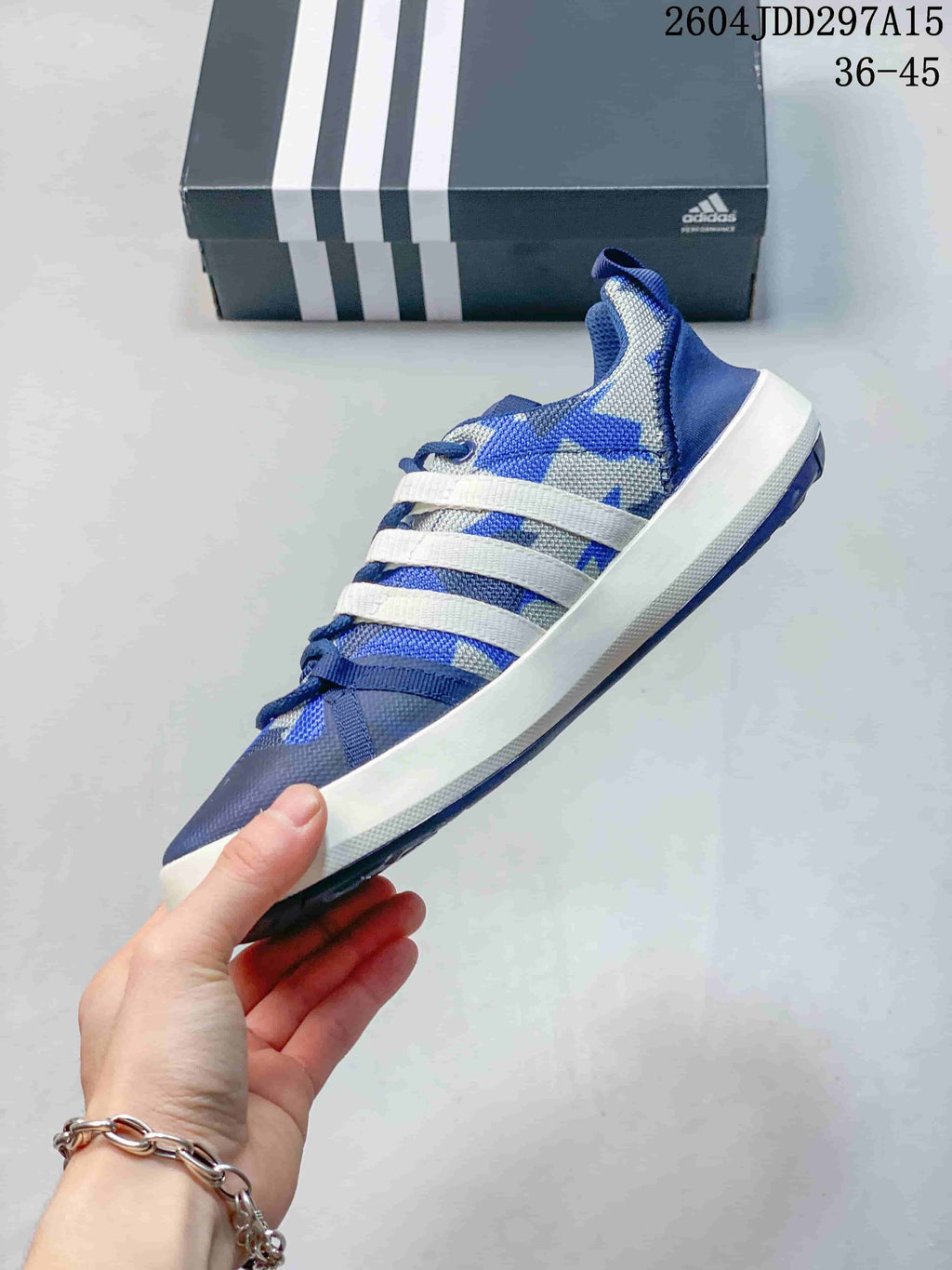 Side profile of the blue and white adidas shoe showing the mesh-like upper, three white side stripes, laces and white midsole.