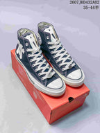 Pair of navy high-top Converse-style sneakers with white laces and decorative patches on a red shoebox