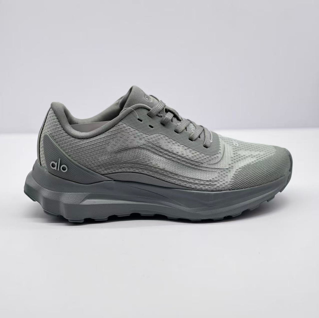Side view of a gray Alo Runner sneaker showing the lace-up upper, layered side detailing, padded collar, and thick outsole.