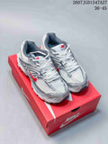 Pair of Nike Air Max Moto 2K sneakers on a red shoebox, showing the white and silver upper with red accents.
