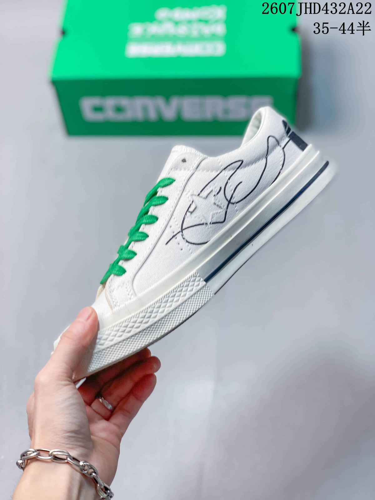 Side view of the white canvas sneaker showing green laces, illustrated graphics, and a rubber sole.