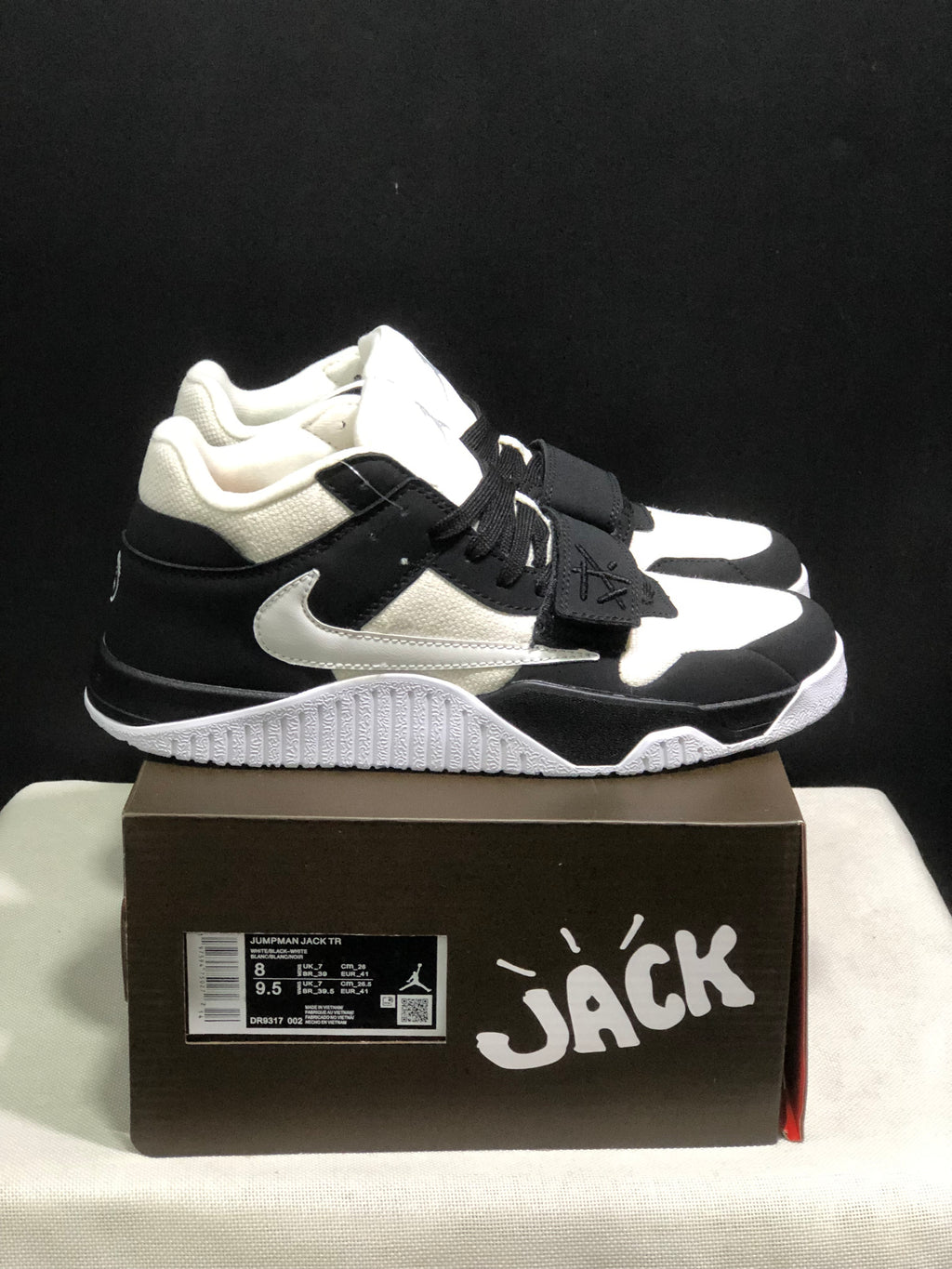 Side view of the black and white sneakers showing the layered upper, side branding, and textured outsole.