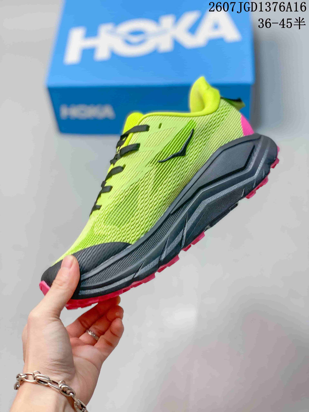 Side view of the green and black running shoe showing the lace-up upper, sculpted midsole, and pink outsole accents.