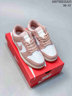 Pair of white and pink low-top sneakers displayed on a red shoebox.