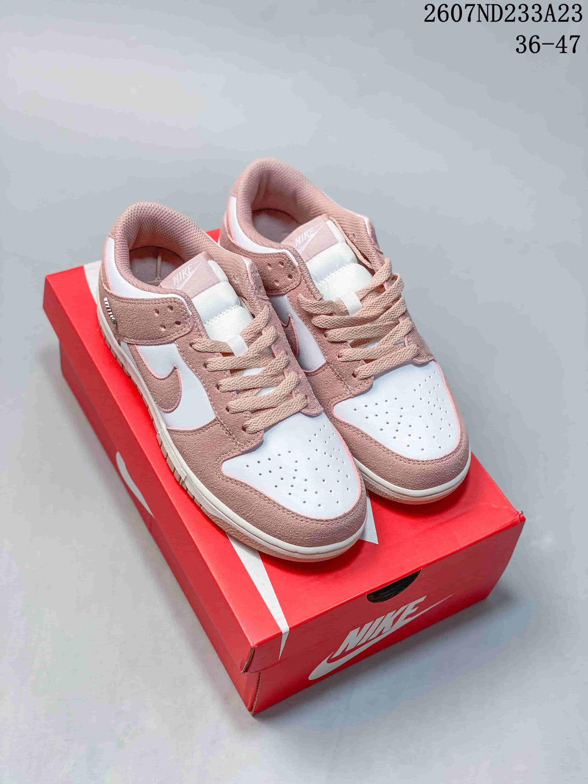 Pair of white and pink low-top sneakers displayed on a red shoebox.