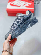 Side view of the gray and black sneaker showing mesh panels, layered overlays, Nike branding, and the chunky outsole.
