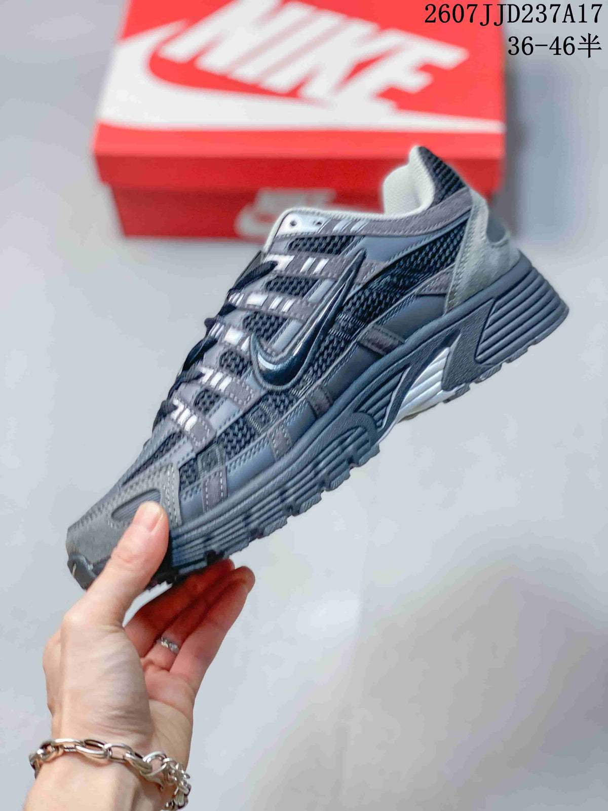Side view of the gray and black sneaker showing mesh panels, layered overlays, Nike branding, and the chunky outsole.