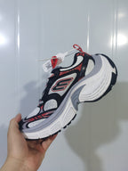 Close-up side view of black, orange, white and gray Skechers 1101 sneakers with mesh panels, layered overlays and a sculpted white sole.