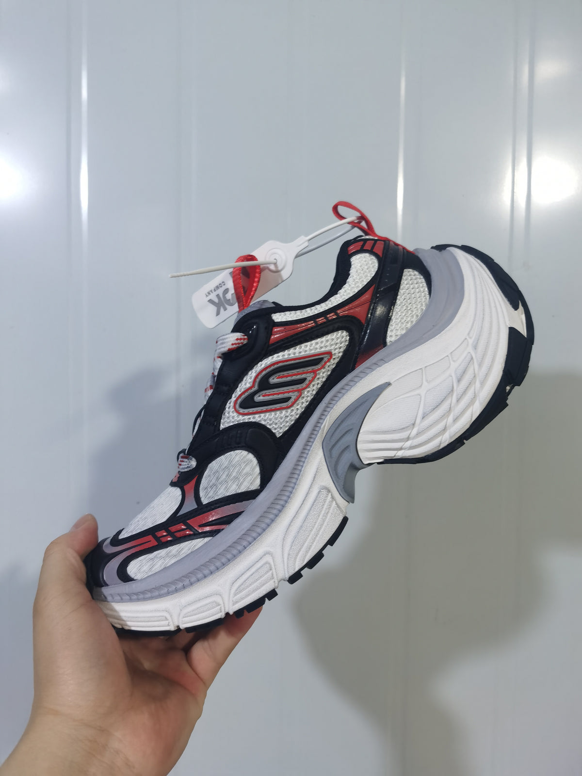 Close-up side view of black, orange, white and gray Skechers 1101 sneakers with mesh panels, layered overlays and a sculpted white sole.