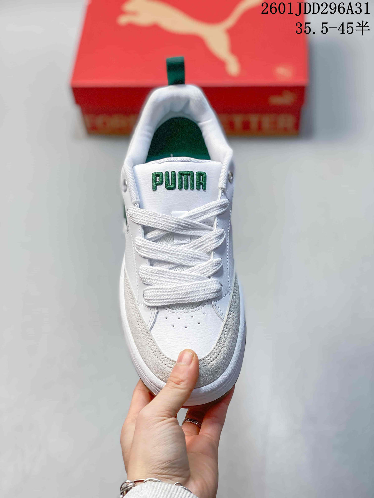 Top view of a white PUMA sneaker with white laces, green tongue branding and perforations on the toe area.
