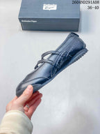 Side profile of the black Mary Jane-style sneaker showing the buckle straps, stitched panels, and low outsole.