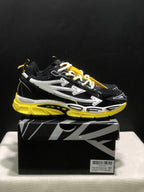 Side profile of a black sneaker with layered white arrow graphics and a bright yellow chunky sole.