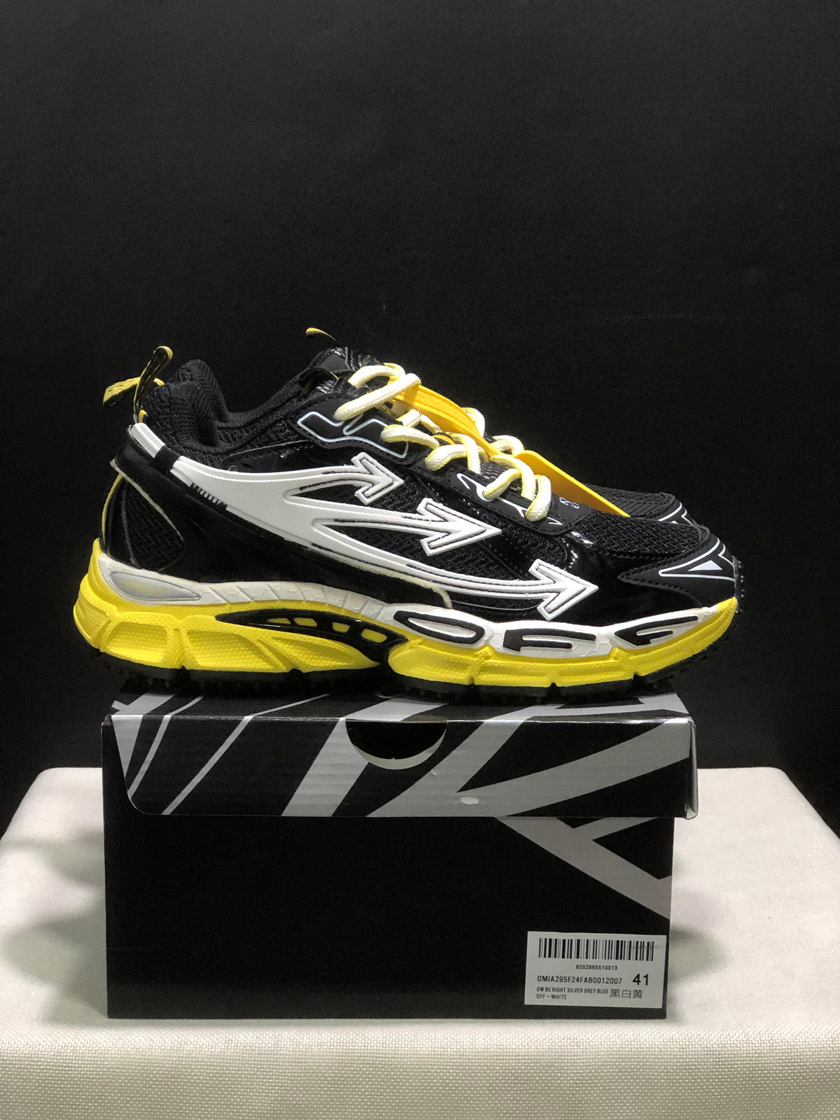 Side profile of a black sneaker with layered white arrow graphics and a bright yellow chunky sole.